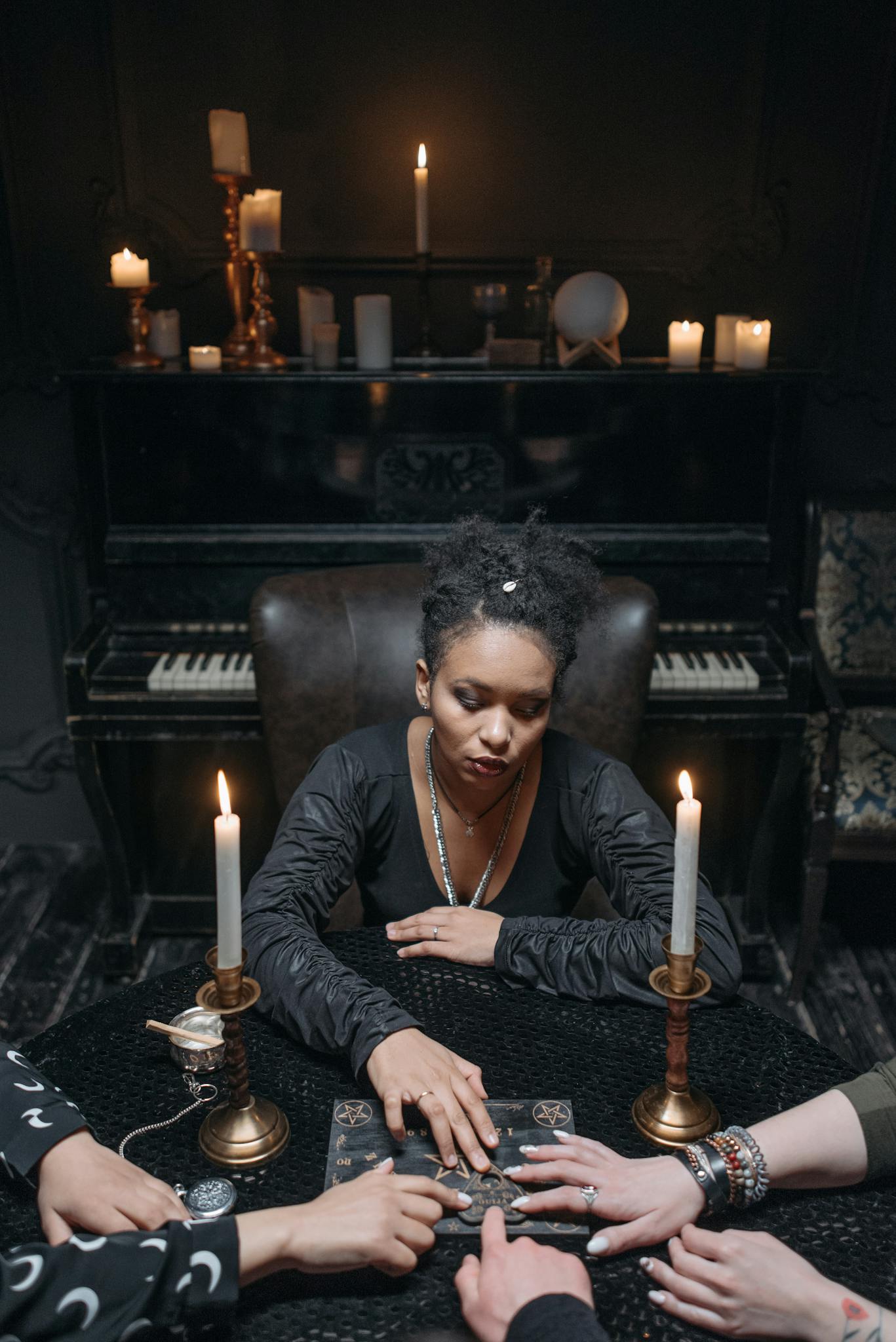 A woman conducts a spiritual session with a Ouija board, surrounded by candles.